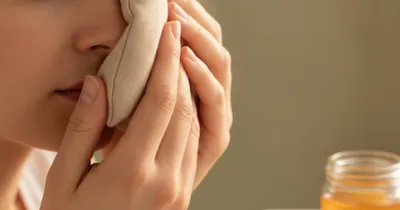 Mains tenant une compresse chaude de camomille sur les yeux pour soigner la blépharite naturellement