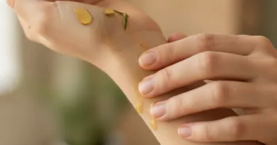 Gros plan d'une main massant le poignet avec de l'huile herbal pour soulager le canal carpien