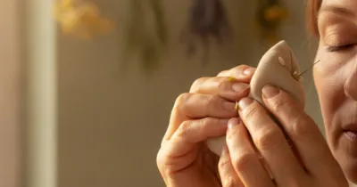 Mains tenant une compresse tiède de camomille près de l'œil fermé — remède naturel contre la sécheresse oculaire