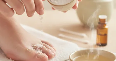 Gros plan sur des mains soignant un ongle incarné avec des remèdes naturels - sel d'Epsom et tea tree