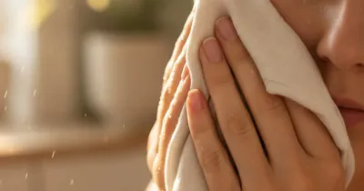 Mains appliquant une compresse froide d'eau de rose sur le visage pour calmer la transpiration excessive